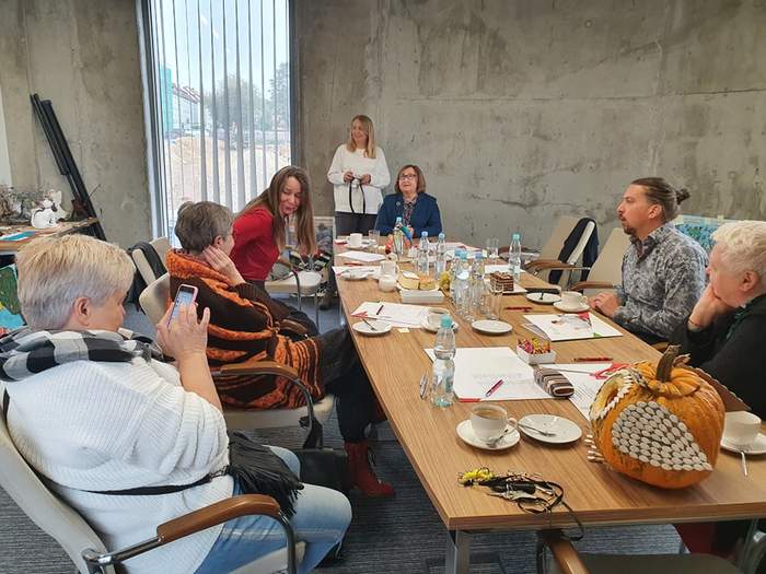 Pokaż zdjęcie: Osoby siedzące przy stole podczas narady