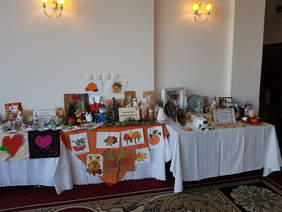 na stołach przykrytych białymi obrusami różne prace artystyczne: stroiki, talerzyki, z papieru, z tkaniny