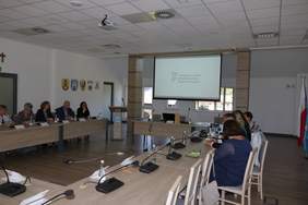 Pokaż zdjęcie: W sali przy stołach ustawionych w podkowę siedzą Dyrektorzy PCPR-ów oraz przedstawiciele PFRON. W głebi na ekranie rozwijanym wyświetlana jest prezentacjia dotycząca zagadnień niepełnosprwności.