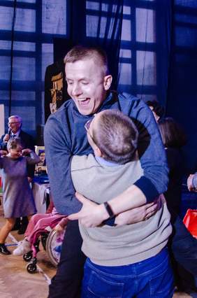 Pokaż zdjęcie: Dwóch mężczyzn padło sobie w objęcia. Cieszą się z powodu wygranej w festiwalu. Przytulają się i uśmiechają się szeroko. 