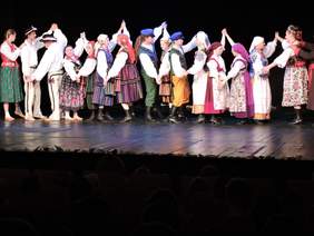 Pokaż zdjęcie: Osoby tańczące na scenie w strojach ludowych