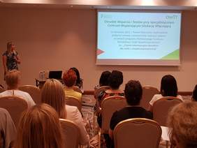 sala konferencyjna, widok siedzących z tyłu, z lewej strony kobieta mówi do mikrofonu