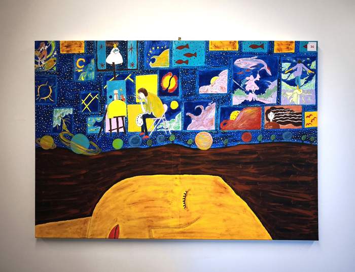 Pokaż zdjęcie: Duży, kolorowy obraz przedstawia surrealistyczną scenę w kosmicznej przestrzeni. W dolnej części widoczna jest ogromna, żółta twarz z zamkniętym okiem, jakby pogrążona we śnie. Nad nią, na tle granatowego nieba pełnego gwiazd, znajduje się postać siedząca przy sztaludze i malująca. Wokół artysty rozmieszczone są liczne prostokątne kadry przypominające obrazy lub wizje – przedstawiają m.in. ryby, planety, postacie ludzkie, fale, słońce i fantastyczne sceny. U dołu widoczne są kolorowe planety oraz ciemna, ziemista powierzchnia. Całość utrzymana jest w intensywnych barwach – dominują granaty, żółcie, pomarańcze i błękity – i tworzy baśniowy, oniryczny klimat.