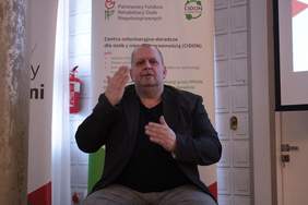 Pokaż zdjęcie: Zdjęcie tłumacza języka migowego, mężczyzna siedzi na krześle