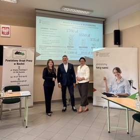 Dwie kobiety i jeden mężczyzna pozują do zdjęcia, stoją pomiędzy rollupami, na których widoczne są logotypy PFRON i PUP w Bochni