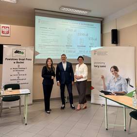 Pokaż zdjęcie: Dwie kobiety i jeden mężczyzna pozują do zdjęcia, stoją pomiędzy rollupami, na których widoczne są logotypy PFRON i PUP w Bochni