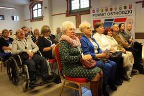 Pokaż zdjęcie: na dużej sali siedzą zaproszeni goście słuchający wystąpień