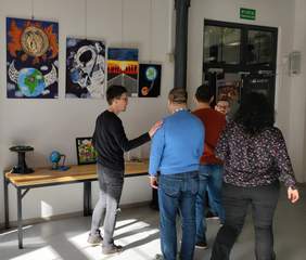 Pokaż zdjęcie: Na zdjęciu widzimy kilka osób podczas oglądania prac na wystawie