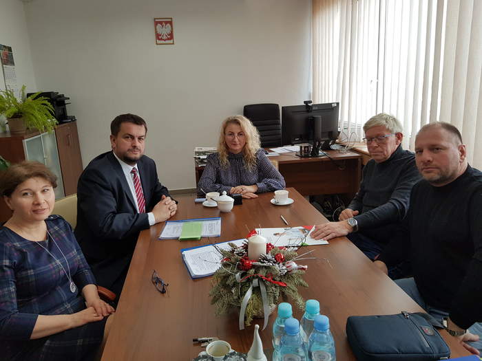 Pokaż zdjęcie: Przy stoliku siedzą osoby podpisujące umowę