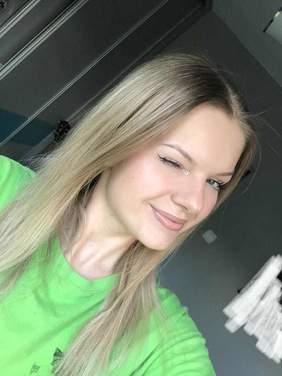 Pokaż zdjęcie: Pani ma zamknięte jedno oko. Jest ubrana w zieloną bluzkę i ma długie blond włosy. 