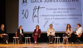 Pokaż zdjęcie: Panel ekspercki podczas gali, na scenie ustawiono krzesła, na których siedzą goście i rozmawiają, zdjęcie sześciu kobiet podczas panelu.
