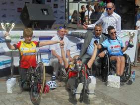 Pokaż zdjęcie: Pamiątkowe zjęcie pierwszej trójki zwycięzców w kategorii "wózkarek hanbike" Kobiet. Za sportowcami stoją Dyrektor Klubu Lekkoatletycznego "Lechia" Gdańsk oraz Dyrektor Oddziału Pomorskiego PFRON.