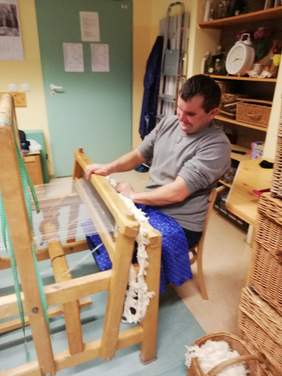 Pokaż zdjęcie: Mężczyzna siedzi przy krosnach tkackich 