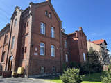 Budynek Starostwa Żagańskiego w Szprotawie, z czerwonej cegły, w tle słoneczna pogoda